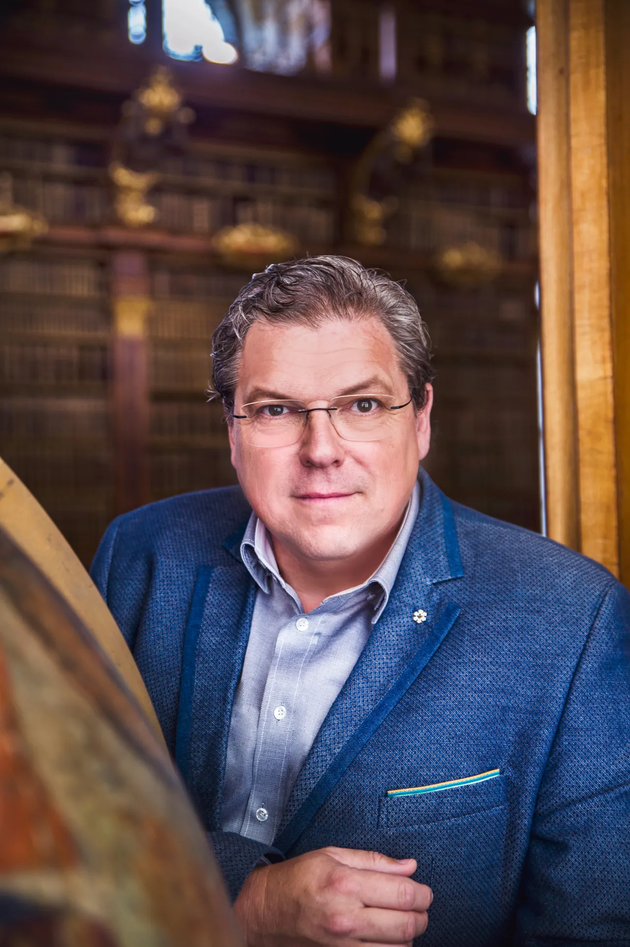 Michael Schade en una biblioteca histórica, junto a un globo terráqueo