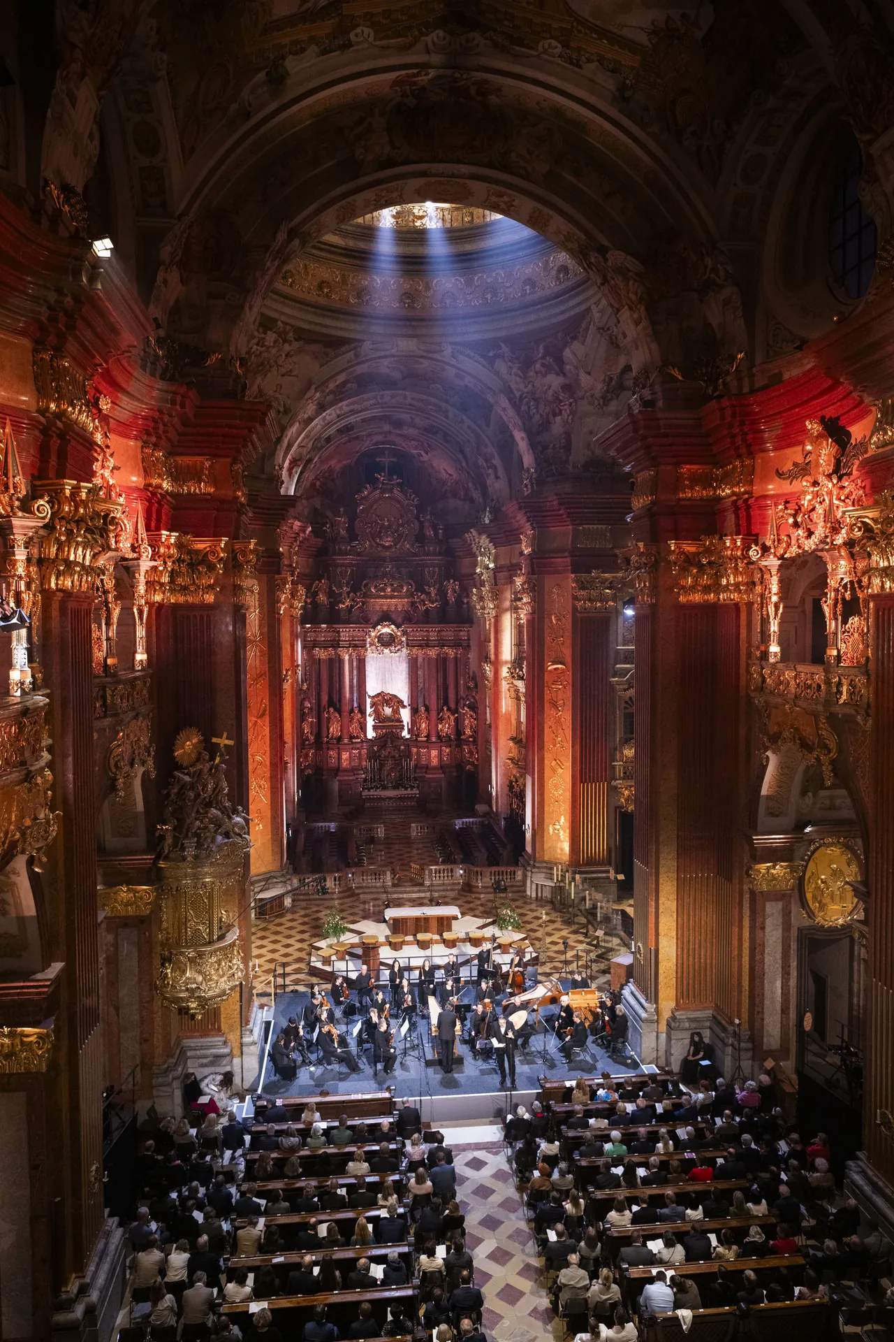 Die Stiftskirche Melk beim Eröffnungskonzert 2026: Lichtstrahlen fallen aus der Kuppel auf die Bühne vor dem Hochaltar, davor das Publikum