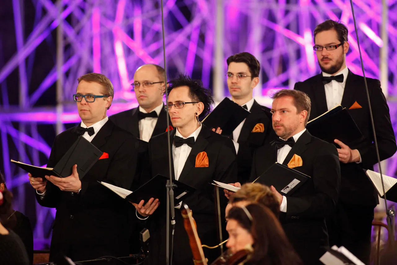 Singers of the Wiener Kammerchor with their scores in front of the purple-lit scaffold installation