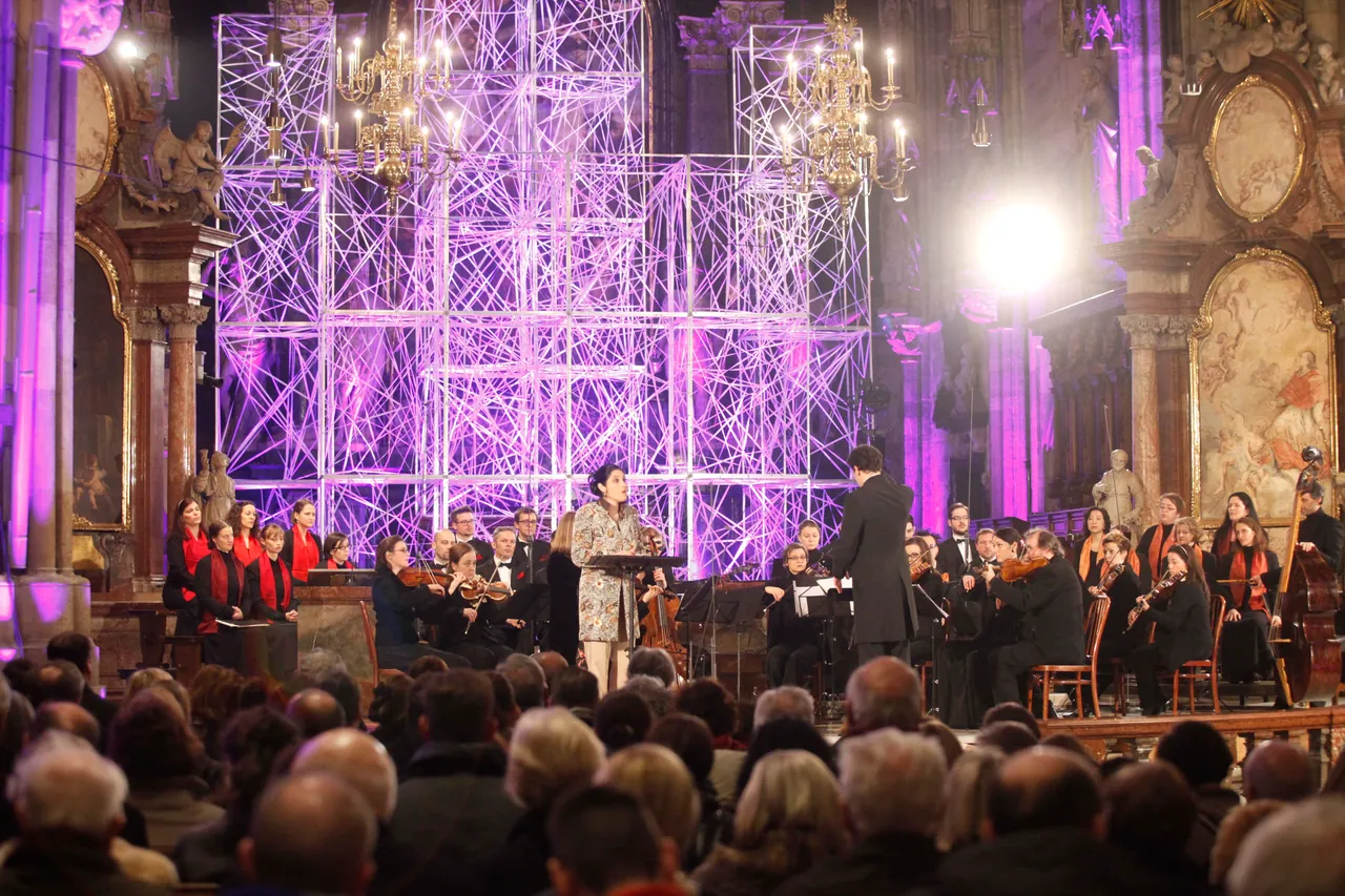 Vivica Genaux sings with the Bach Consort Wien under Rubén Dubrovsky in front of a purple-lit scaffold installation in St. Stephen’s Cathedral, with the Wiener Kammerchor at the sides and the audience in front